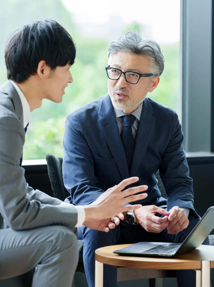 オフィスでノートパソコンを使いながら相談するビジネスマン