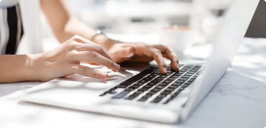 ノートパソコンのキーボード操作をしている女性の手元の写真